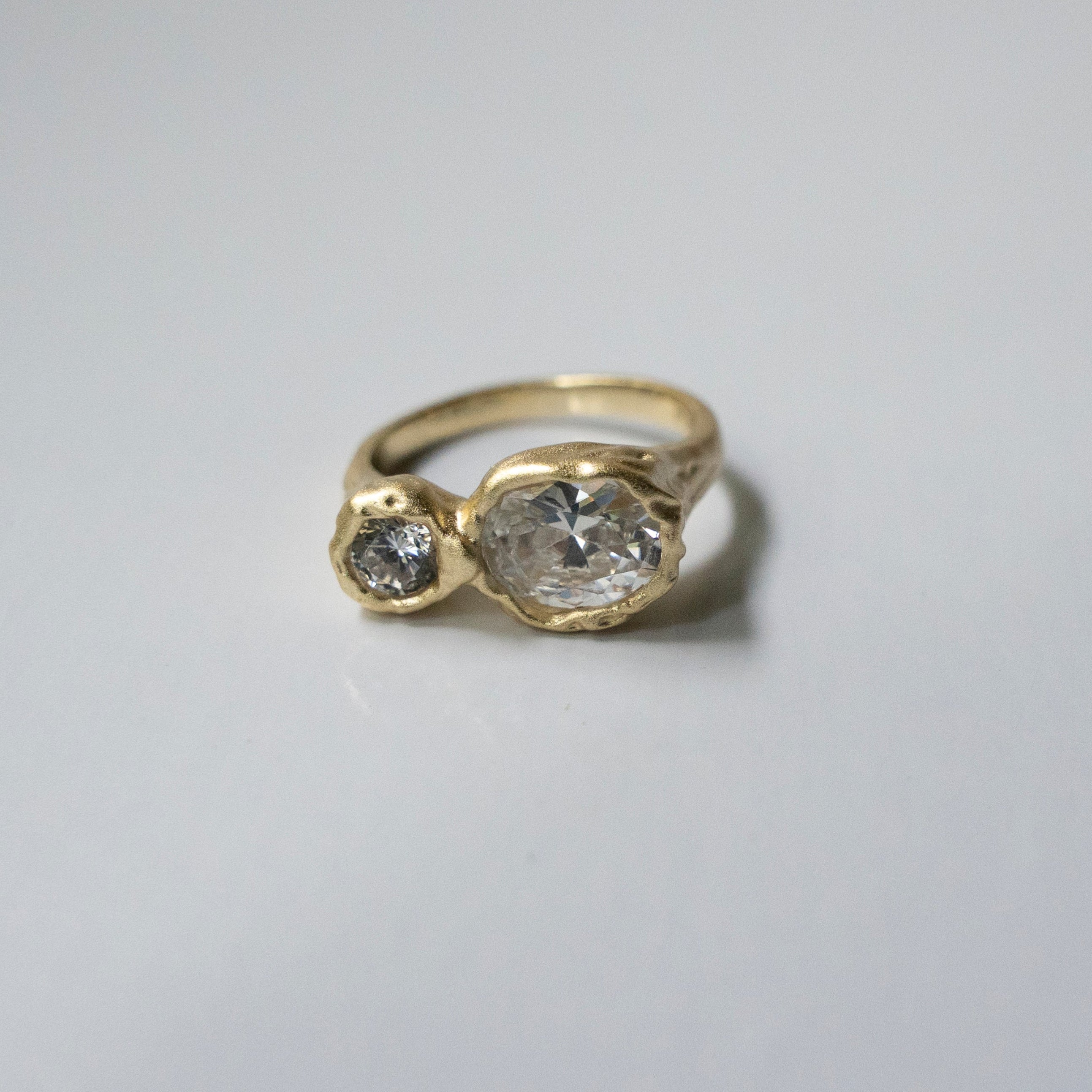 Gold ring with two cz on a light gray background