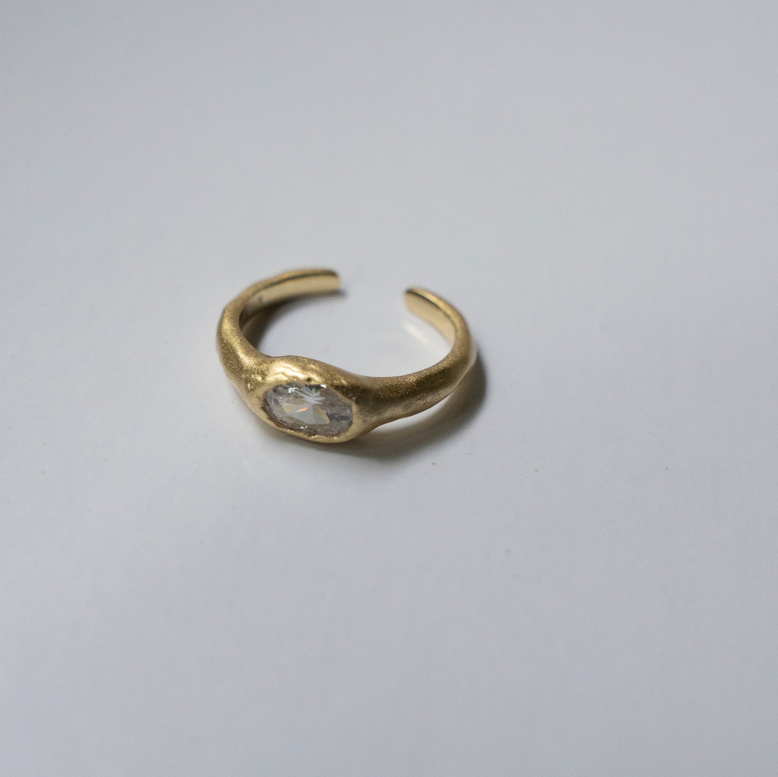 Gold ring with a clear gemstone on a white background