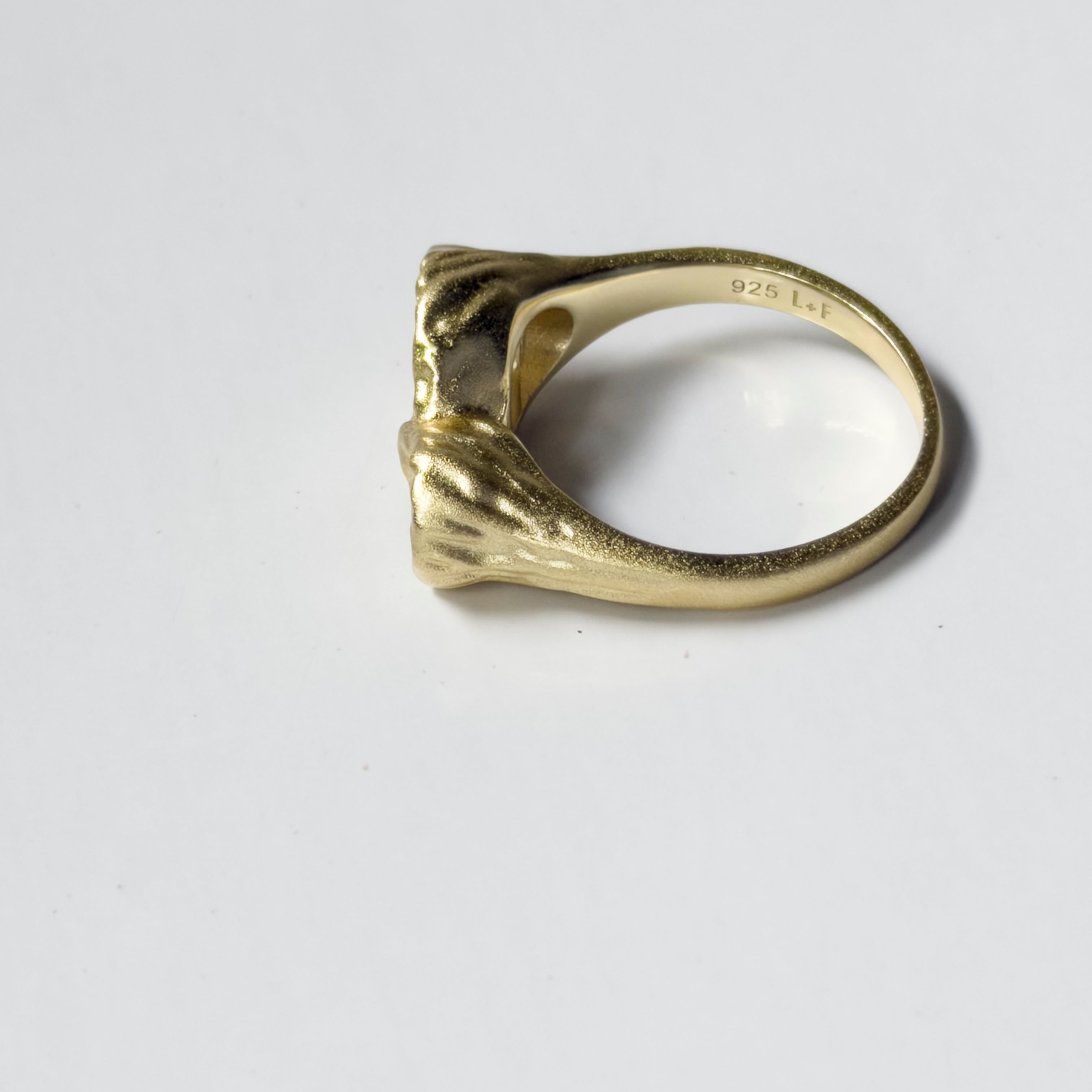Gold ring with a unique design on a white background